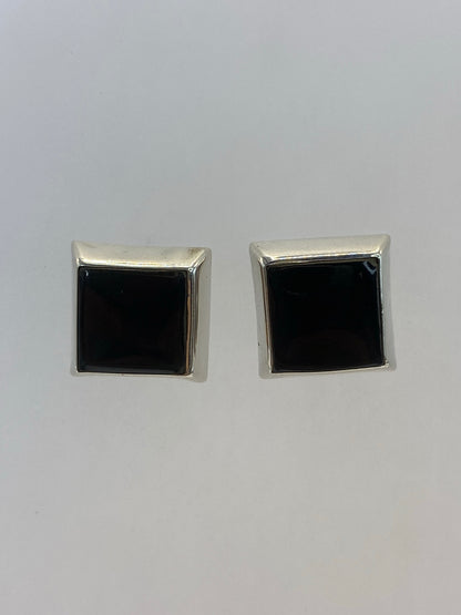 Par de aretes de plata 925 con piedra negra engastada, vistos de frente sobre fondo blanco