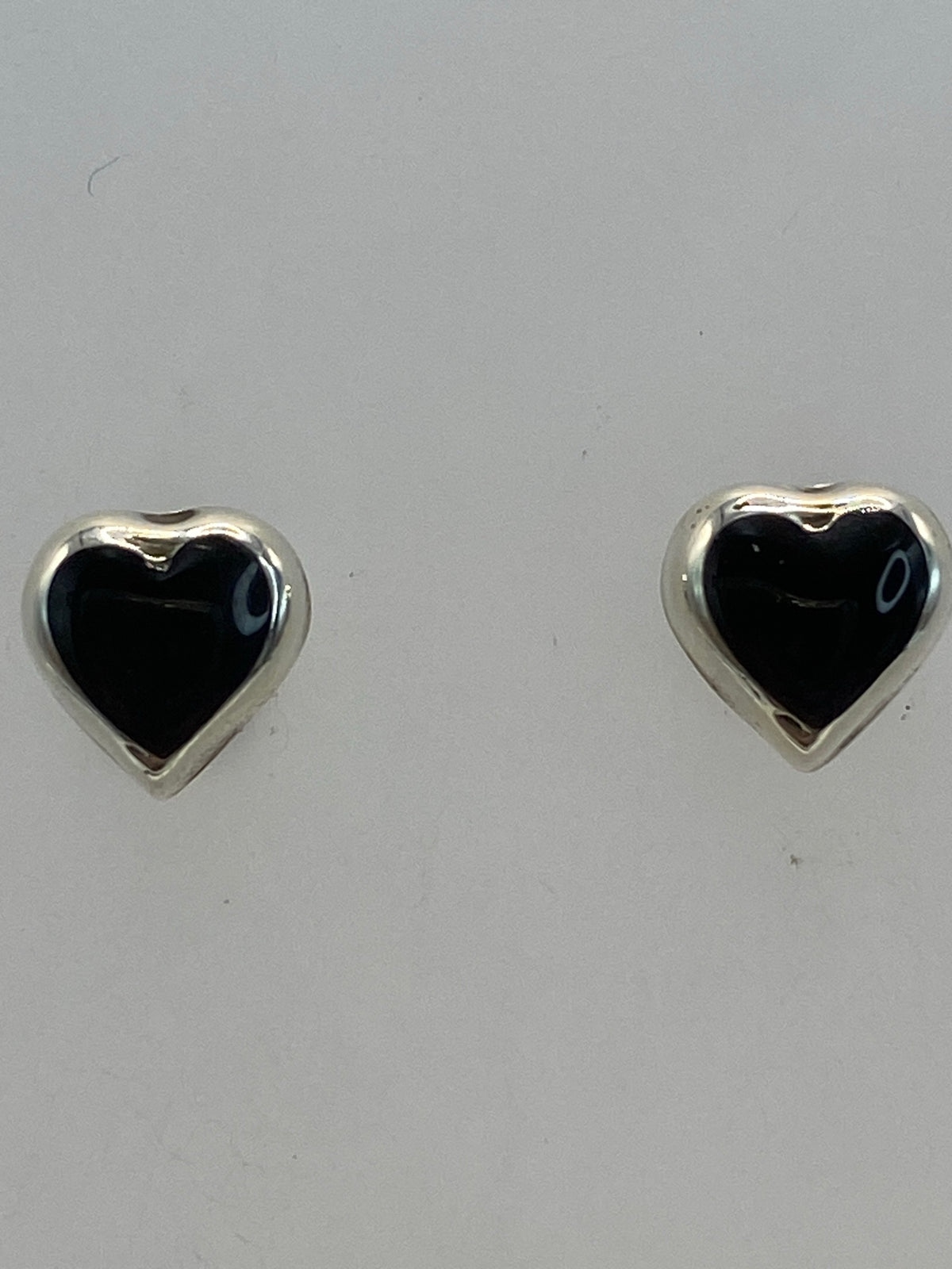 Aretes de plata con piedra negra, vista frontal y lateral sobre fondo blanco