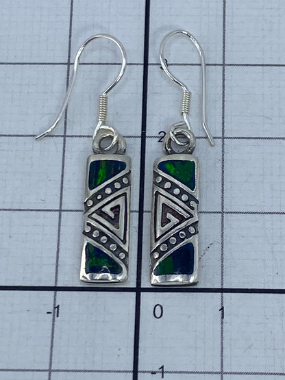 Dos aretes sobre fondo blanco con luz natural, ópalo de fuego verde iridiscente en plata 950