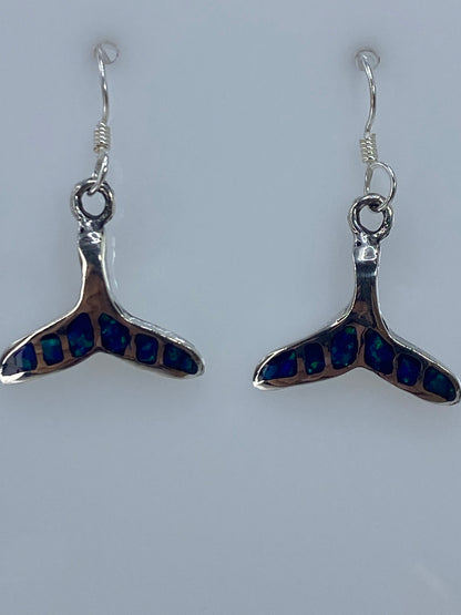 Par de aretes de plata 950 con Ópalo de Fuego azul engastado, colgando sobre fondo blanco