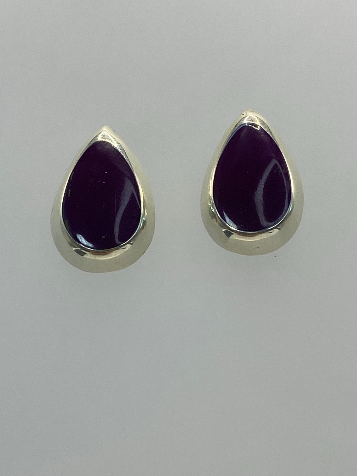 Detalle lateral de aretes de plata con incrustación de piedra morada