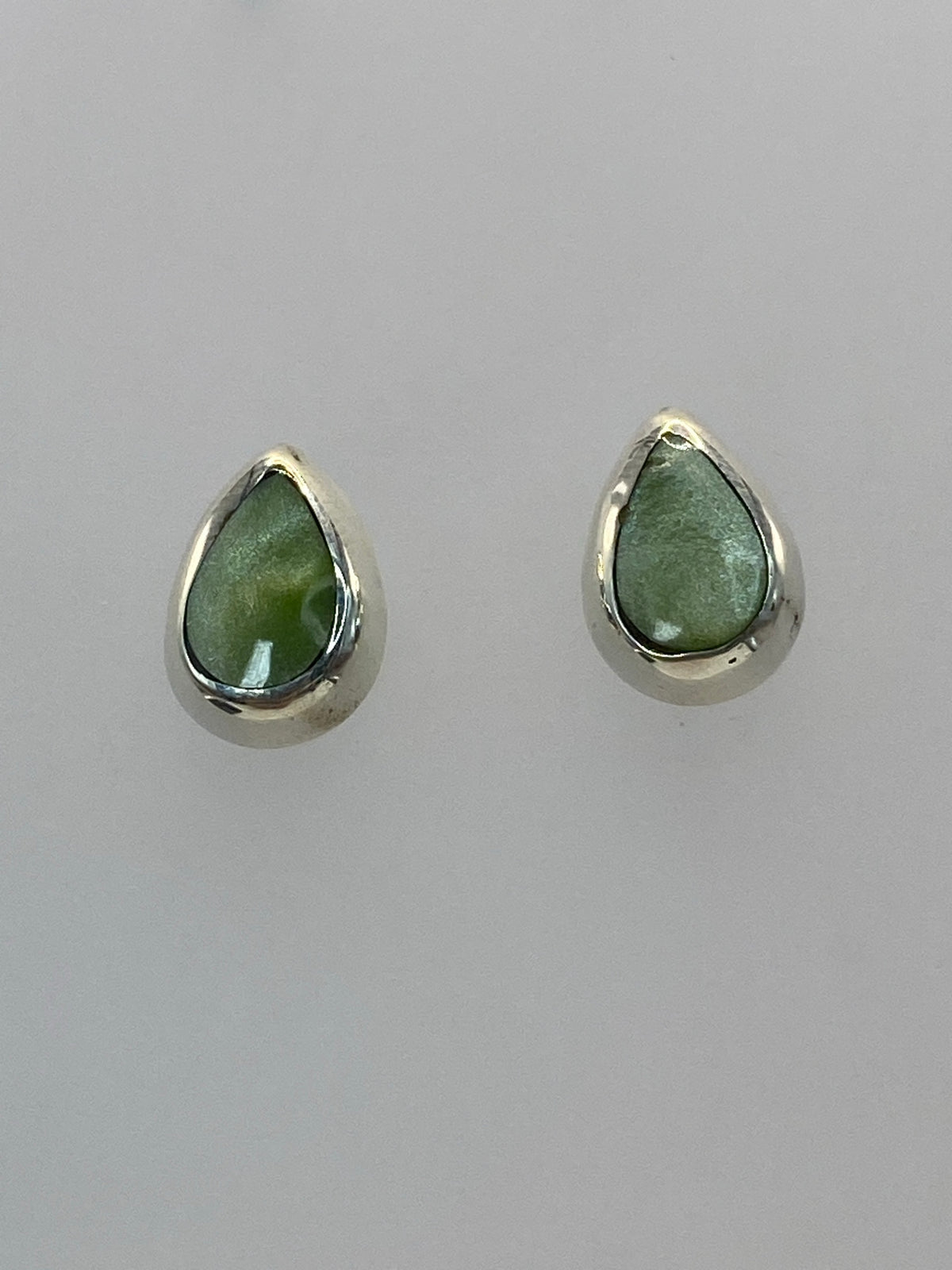 Detalle frontal de los dos aretes mostrando la piedra natural y el engaste de plata
