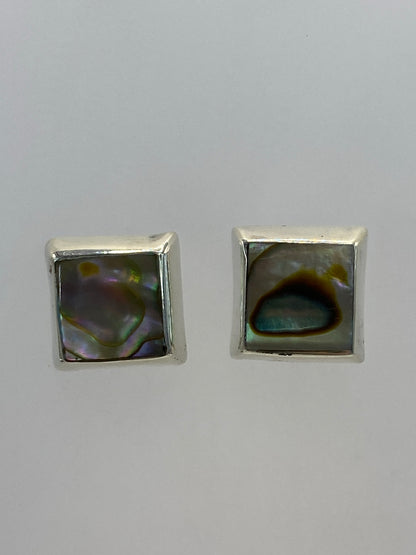 Par de aretes de plata cuadrados con piedra multicolor, posados en la palma de la mano