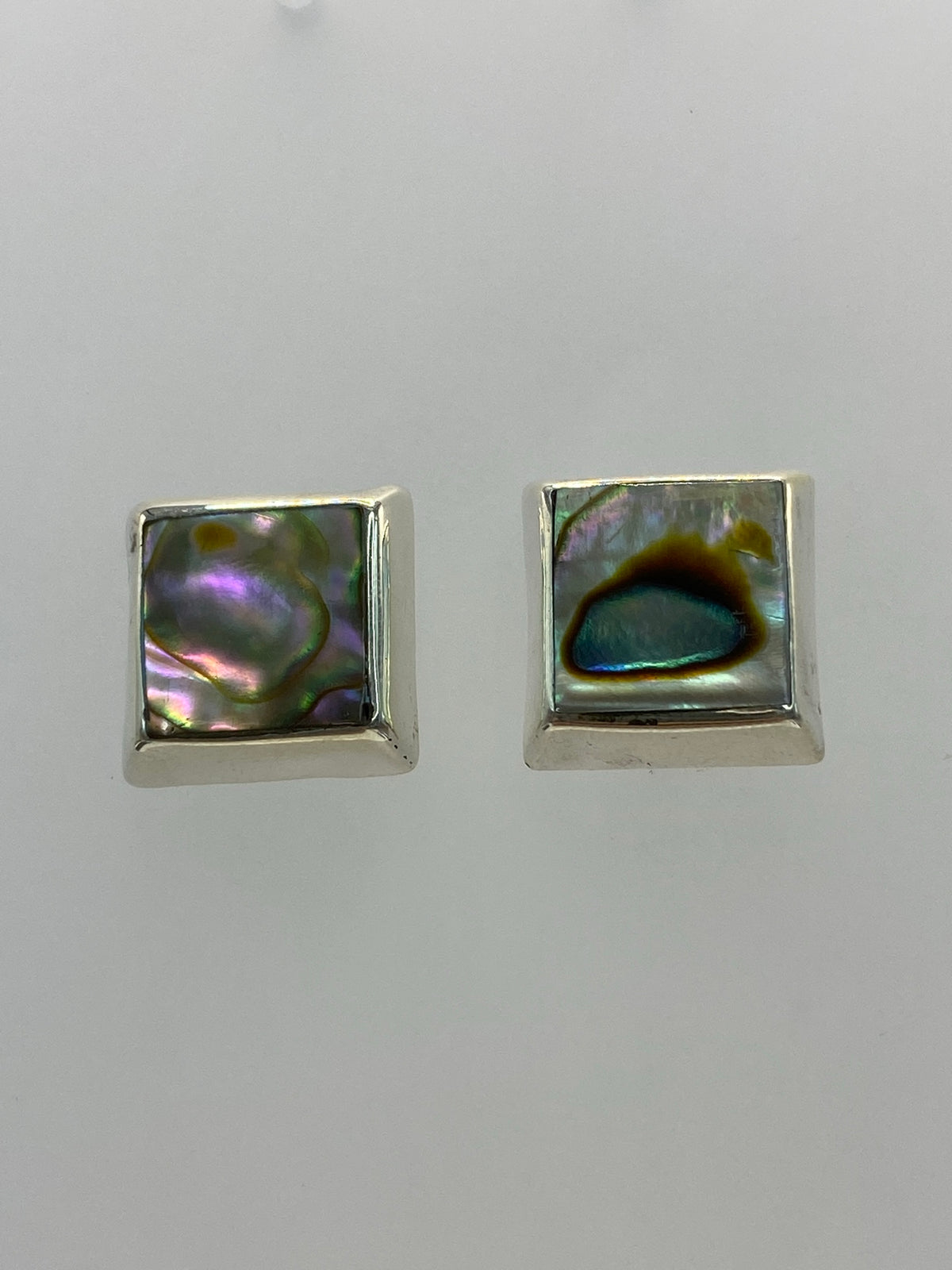 Detalle frontal de los aretes mostrando la incrustación de piedra y el pulido de la plata