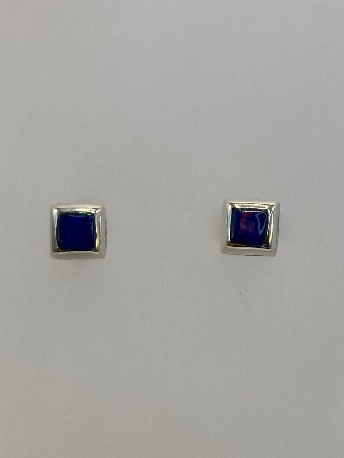 Par de aretes de plata 950 con ópalo de fuego azul, broche de tuerca, sobre fondo blanco