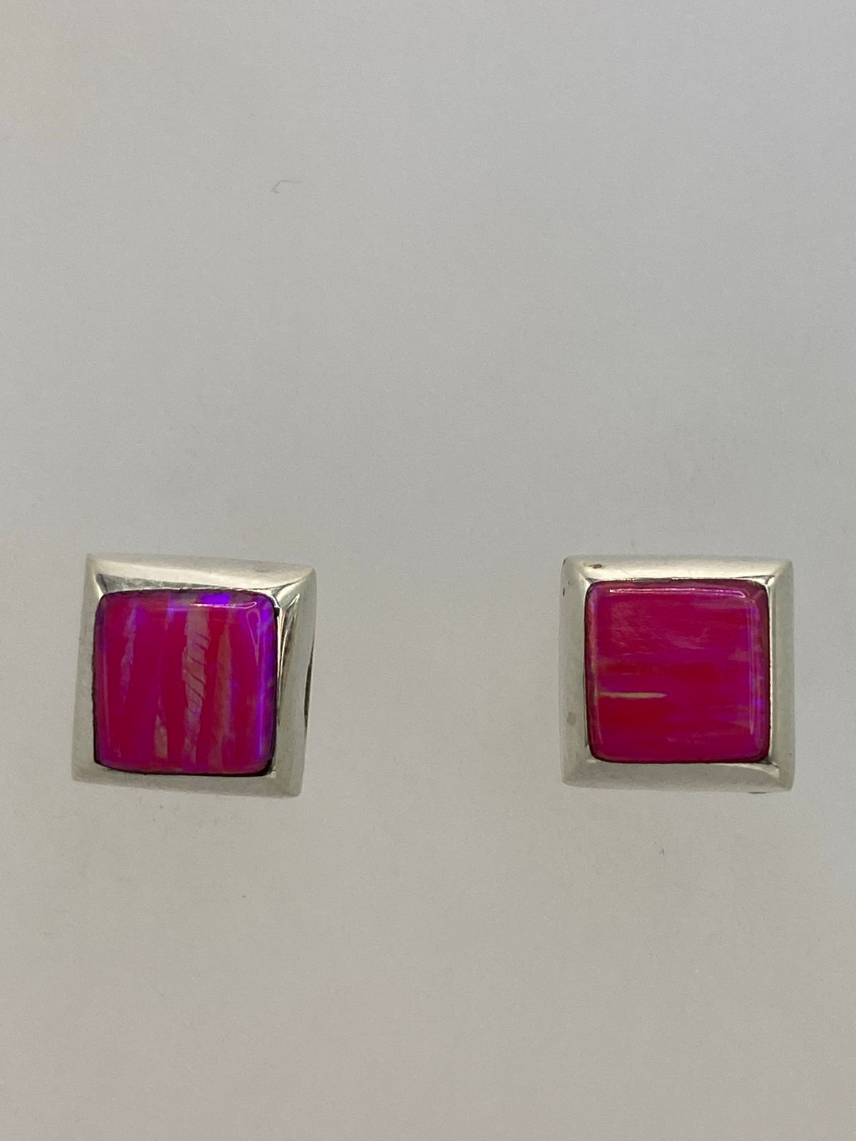 Aretes de plata 925 sobre fondo azul, mostrando el brillo mineral del ópalo