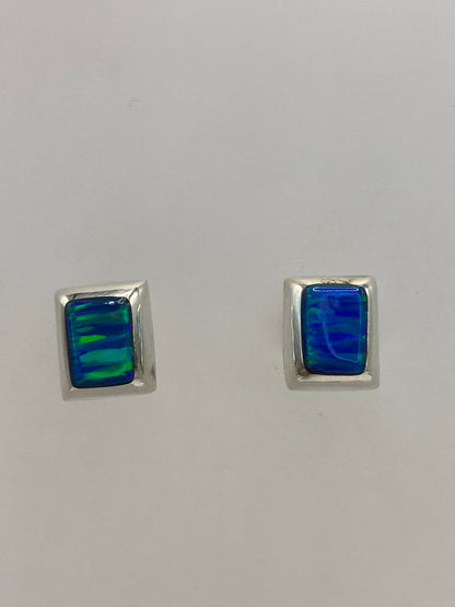 Vista frontal del par de aretes delicados con piedra azul engastada