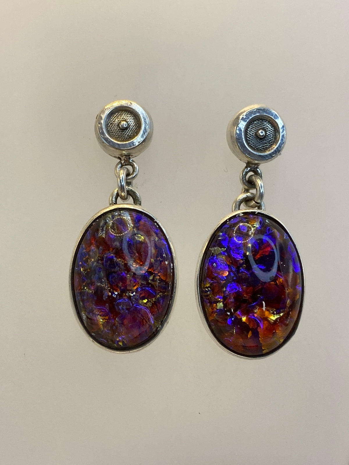 Detalle del ópalo de fuego multicolor en los aretes mostrando rojo, naranja, amarillo y morado