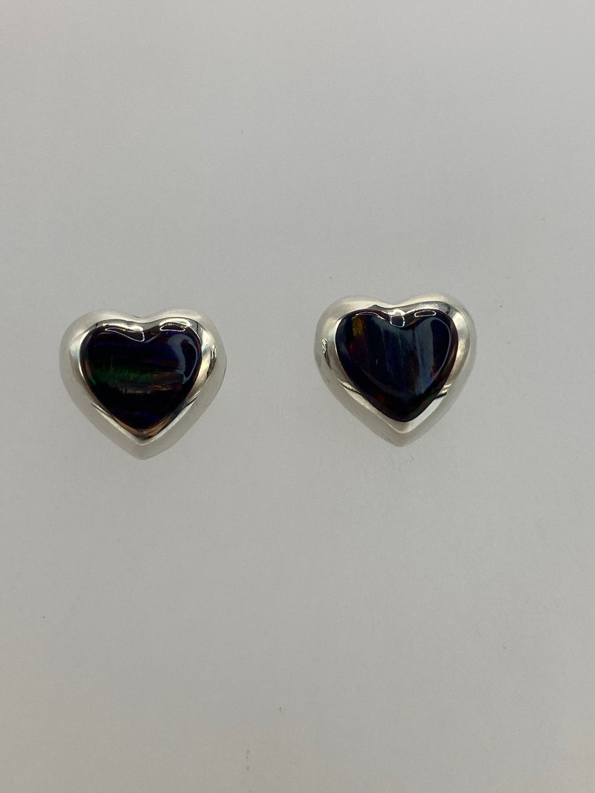 Detalle del engaste a mano del ópalo de fuego en aretes pequeños de plata