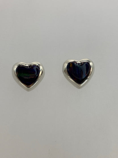 Detalle del engaste a mano del ópalo de fuego en aretes pequeños de plata