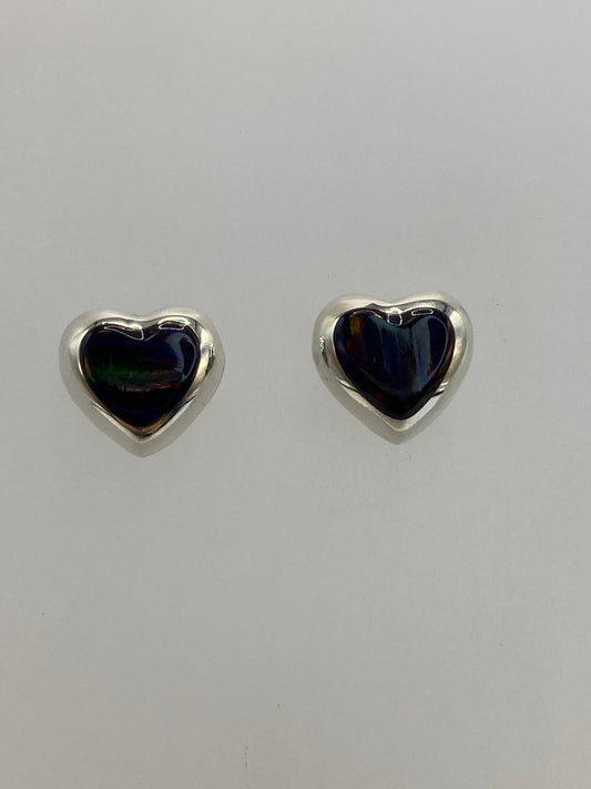 Detalle del engaste a mano del ópalo de fuego en aretes pequeños de plata