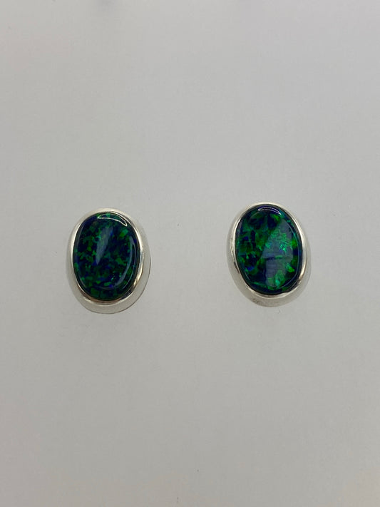 Aretes sobre fondo blanco mostrando el engaste de plata y la piedra verde