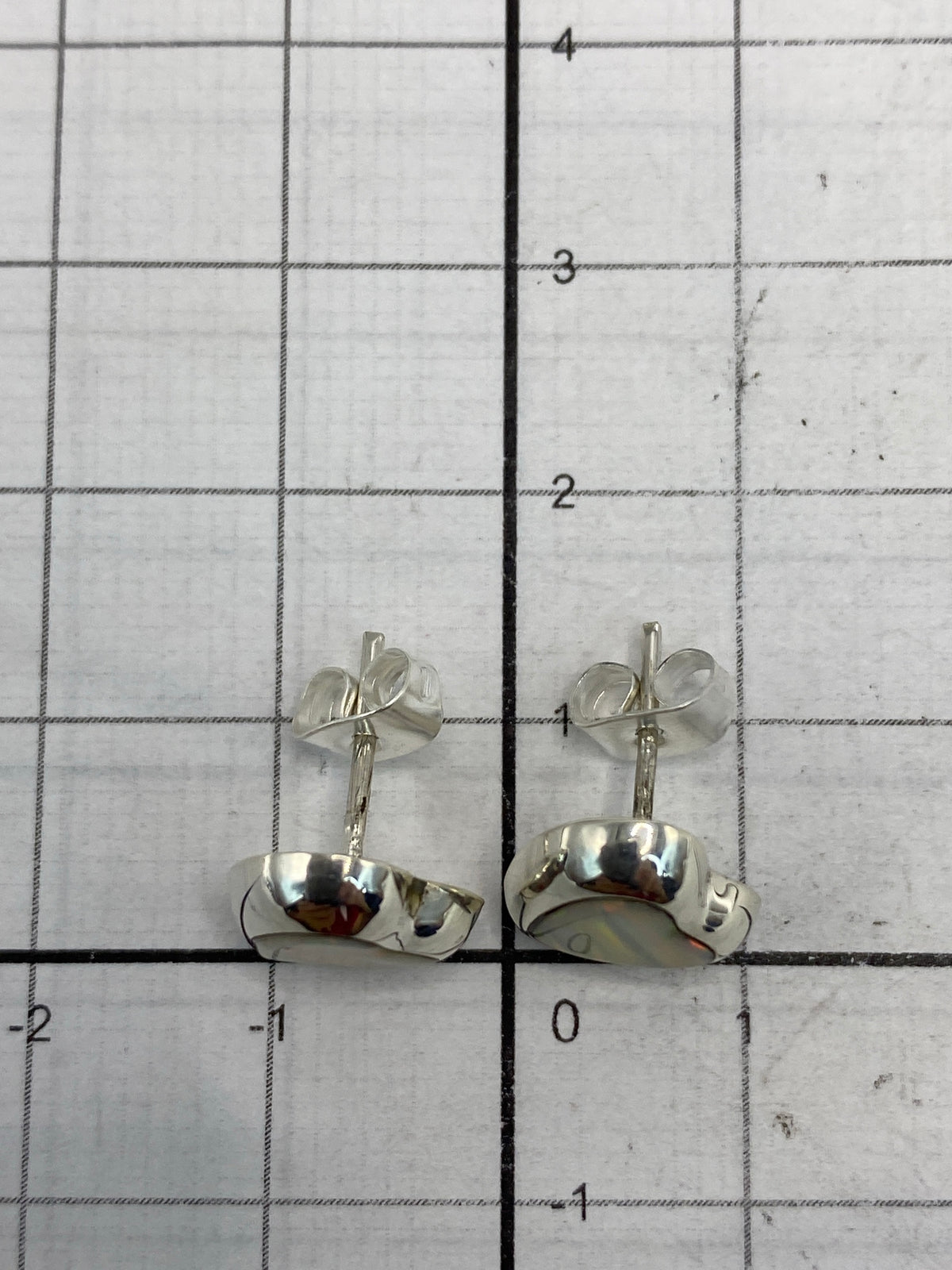 Reverso de los aretes mostrando el Quinto 925 y el poste con mariposa