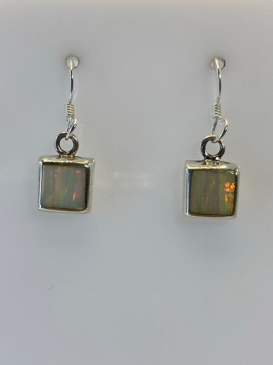 Aretes de plata con ópalo de fuego multicolor, mostrando reflejos naranjas y amarillos