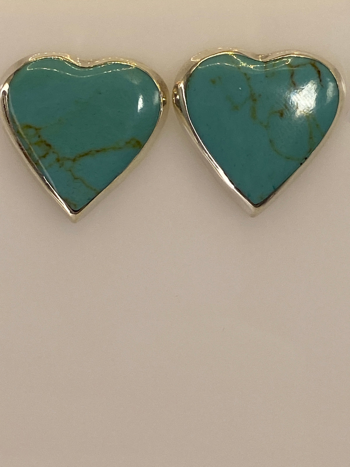 Aretes de plata con turquesa en la mano mostrando el tamaño discreto de 1.8 cm