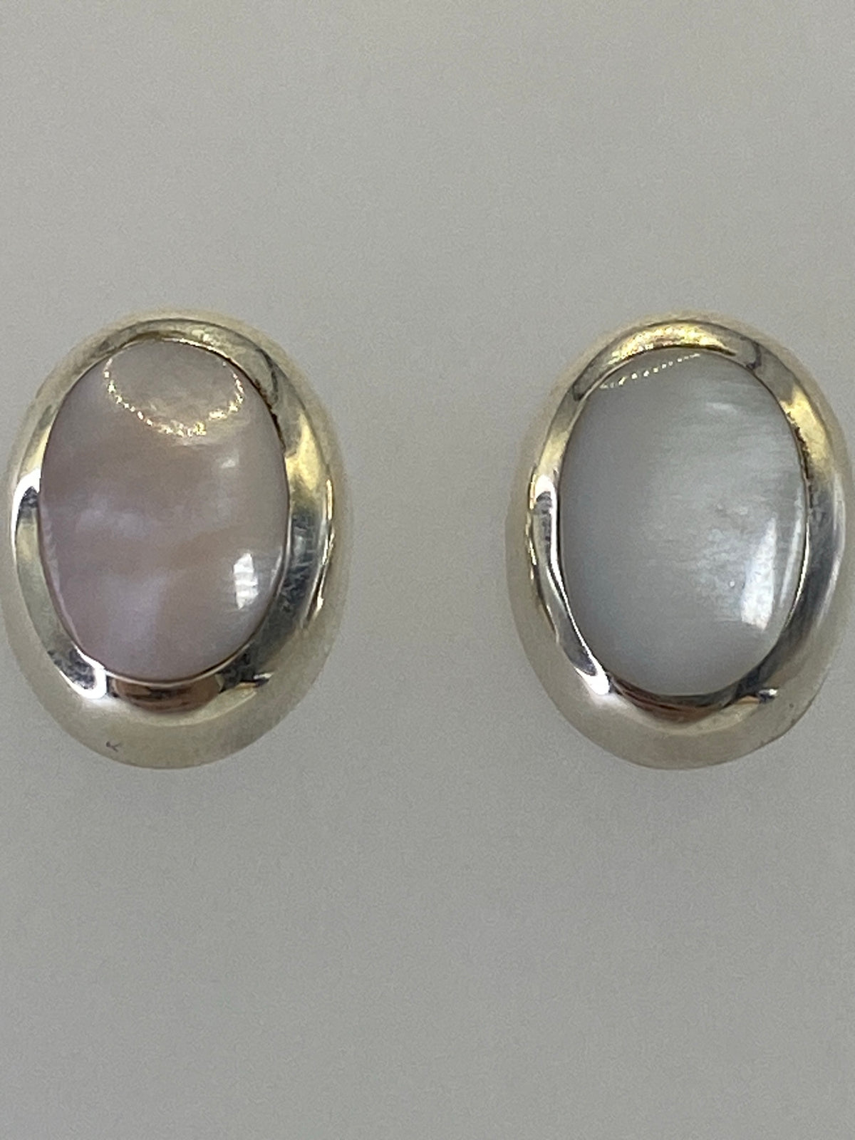 Aretes de plata con piedra colocados en la oreja, mostrando el tamaño real