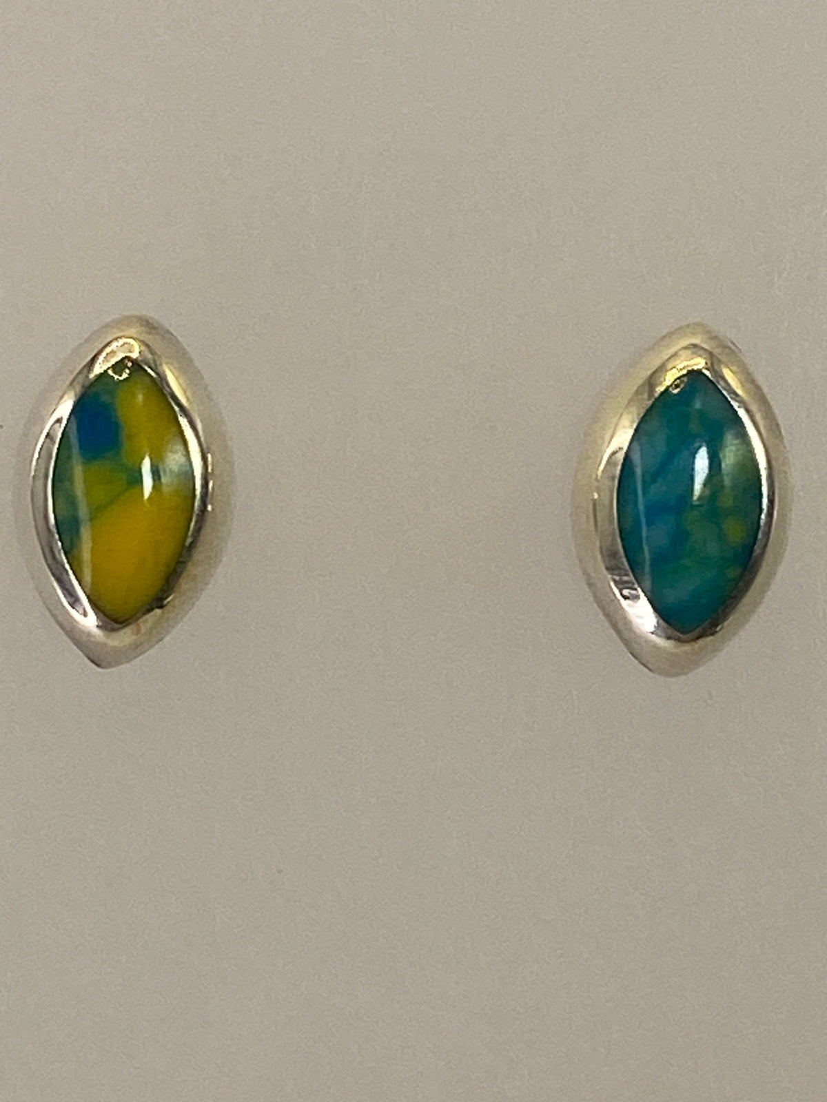 Aretes en la mano mostrando el tamaño real de 1.5 cm