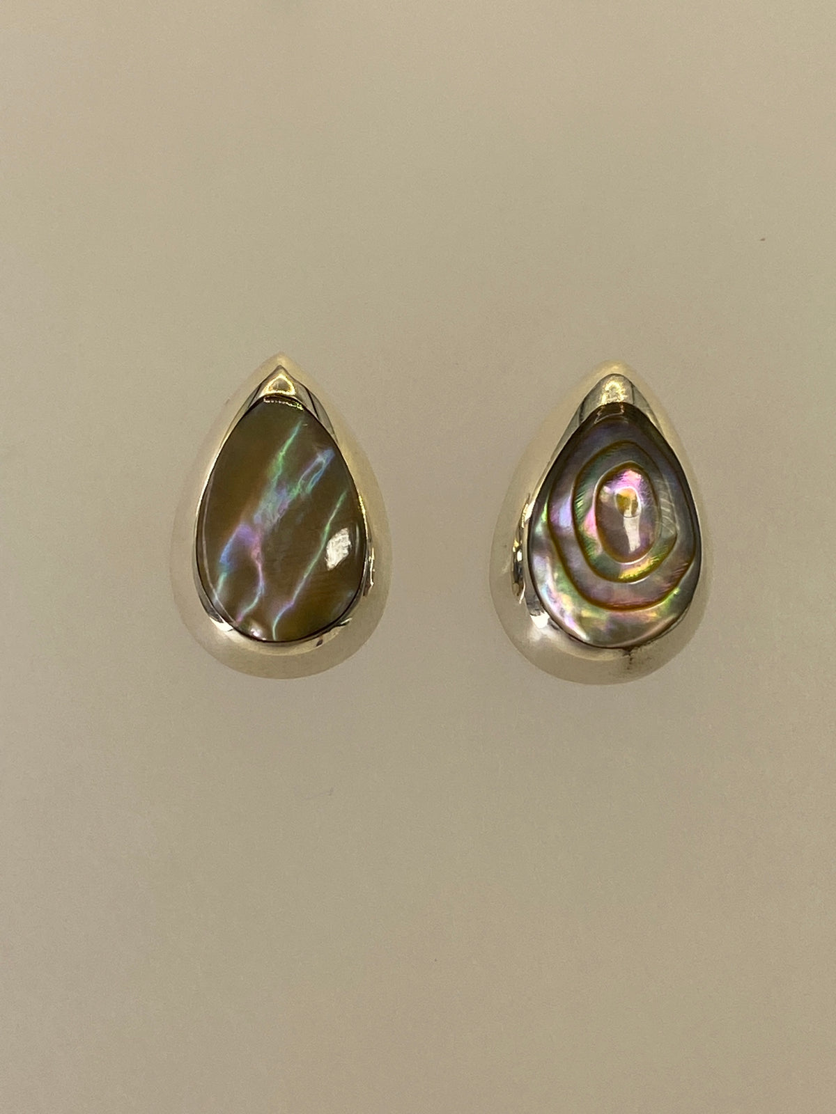 Detalle de los aretes mostrando la incrustación de piedra multicolor con reflejos de color