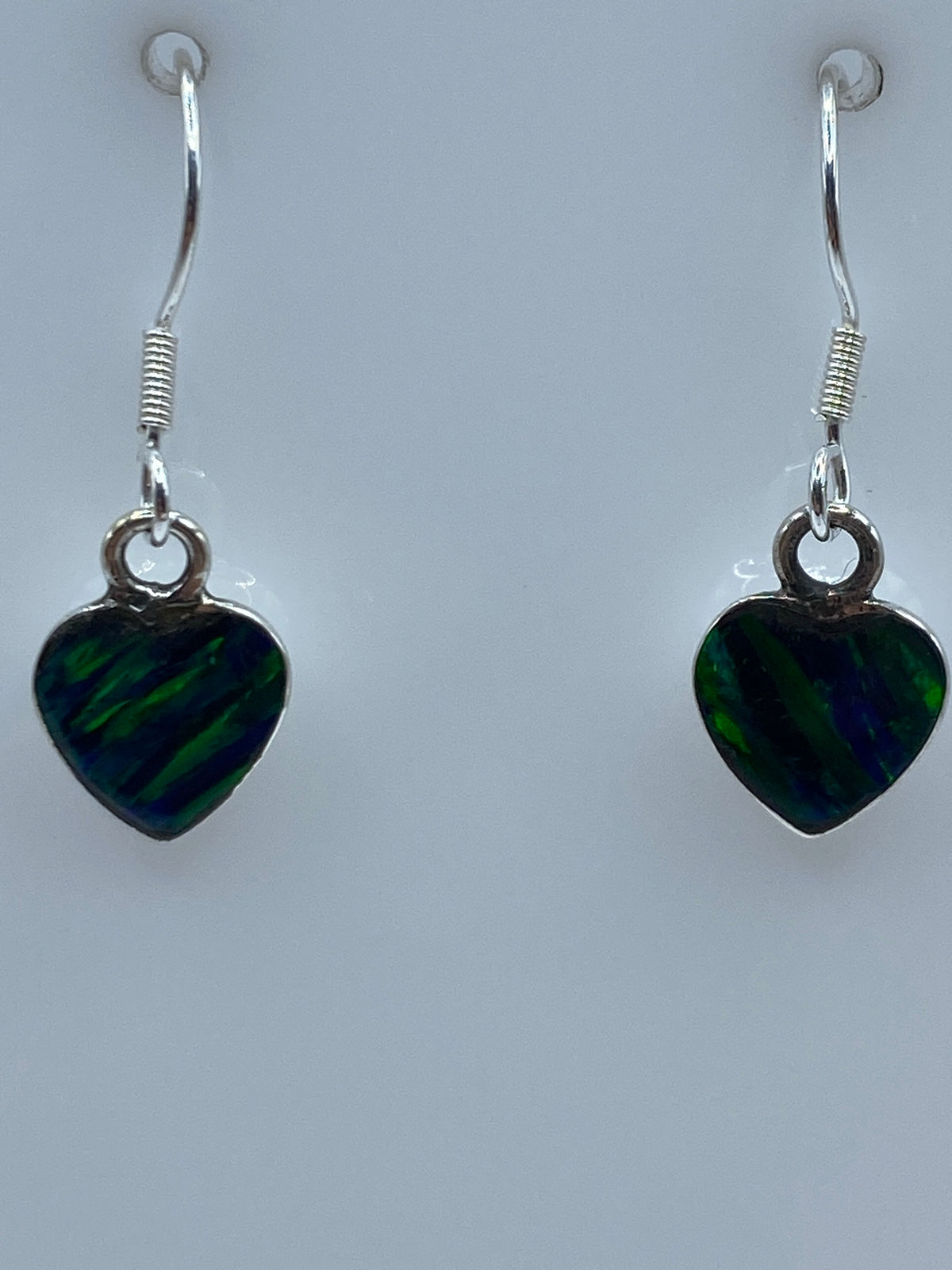 Aretes en la mano mostrando el brillo y color verde del ópalo