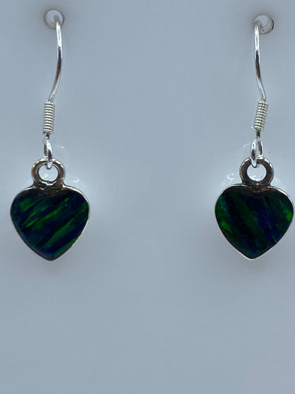 Aretes en la mano mostrando el brillo y color verde del ópalo