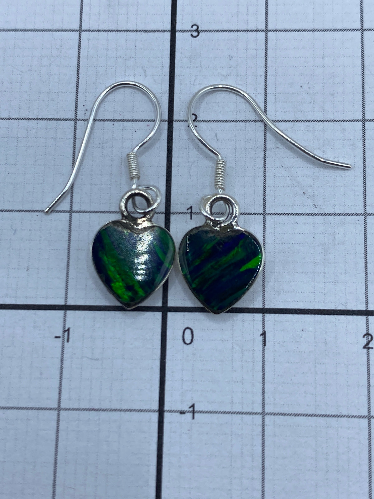 Aretes de plata sobre fondo blanco con medida de referencia (2.3 cm)