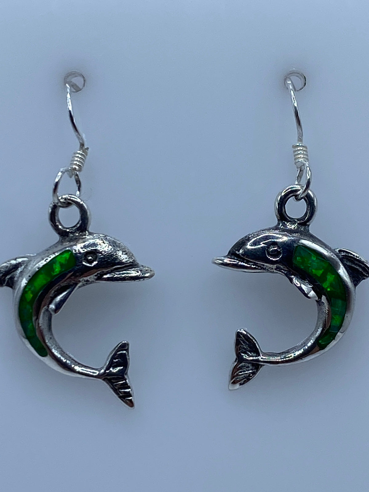 Aretes colgando mostrando el opalo de fuego brillando a la luz