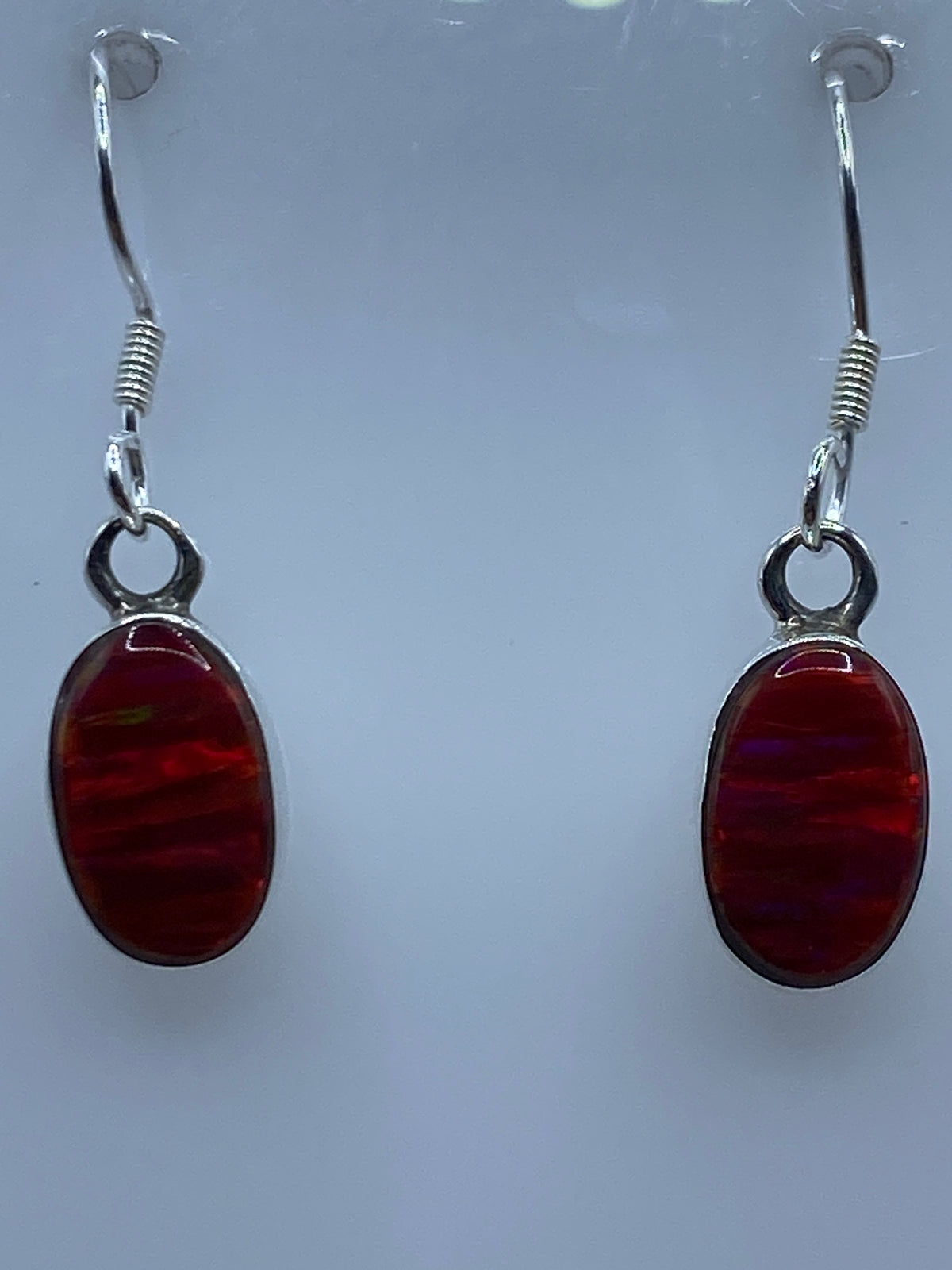 Vista frontal del par de aretes mostrando los tonos rojo, naranja y amarillo del Opalo