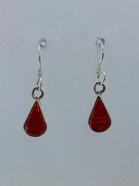 Aretes de plata con ópalo de fuego rojo, colgando frente a fondo blanco