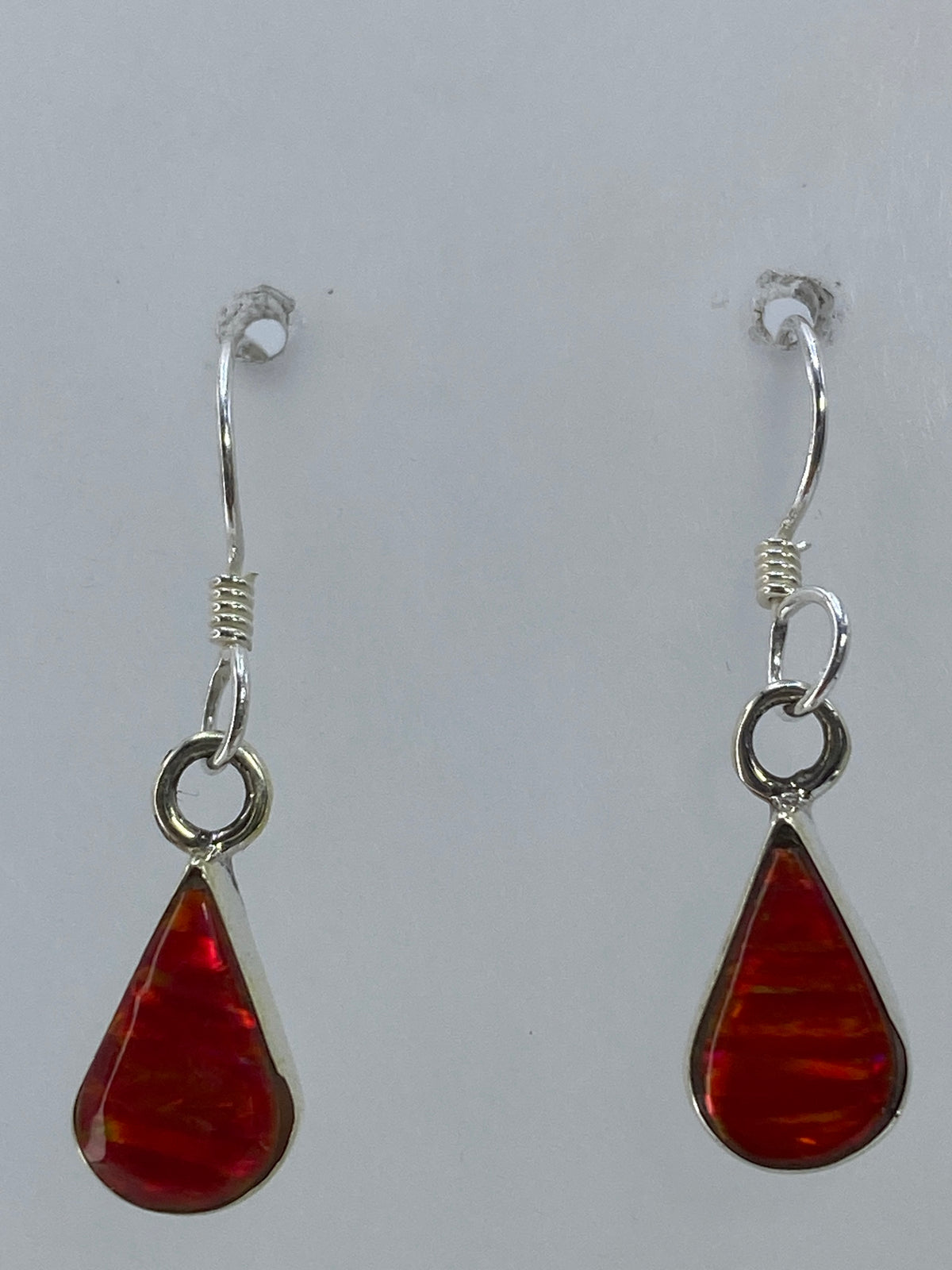 Los dos aretes con ópalo rojo sobre una regla de medición — 2.8 cm de largo