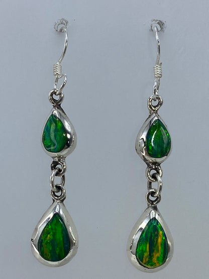 Aretes puestos en oreja, mostrando la cascada y los reflejos verdes dorados del ópalo