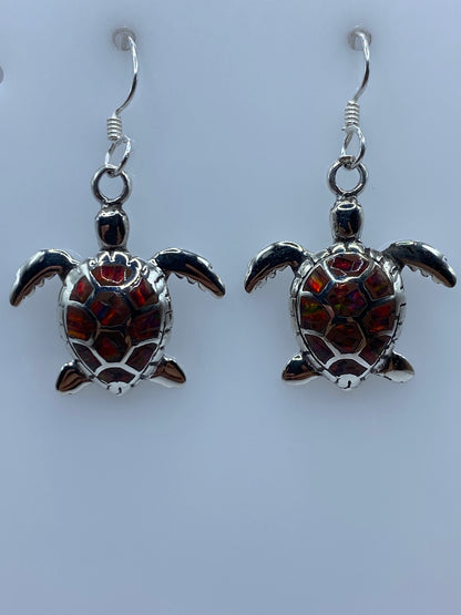 Par de aretes de plata con ópalo de fuego multicolor, colgando sobre fondo blanco