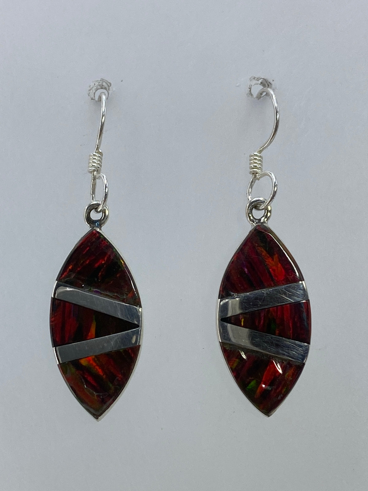 Par de aretes de plata 950 con ópalo de fuego multicolor engastado, colgando sobre fondo blanco