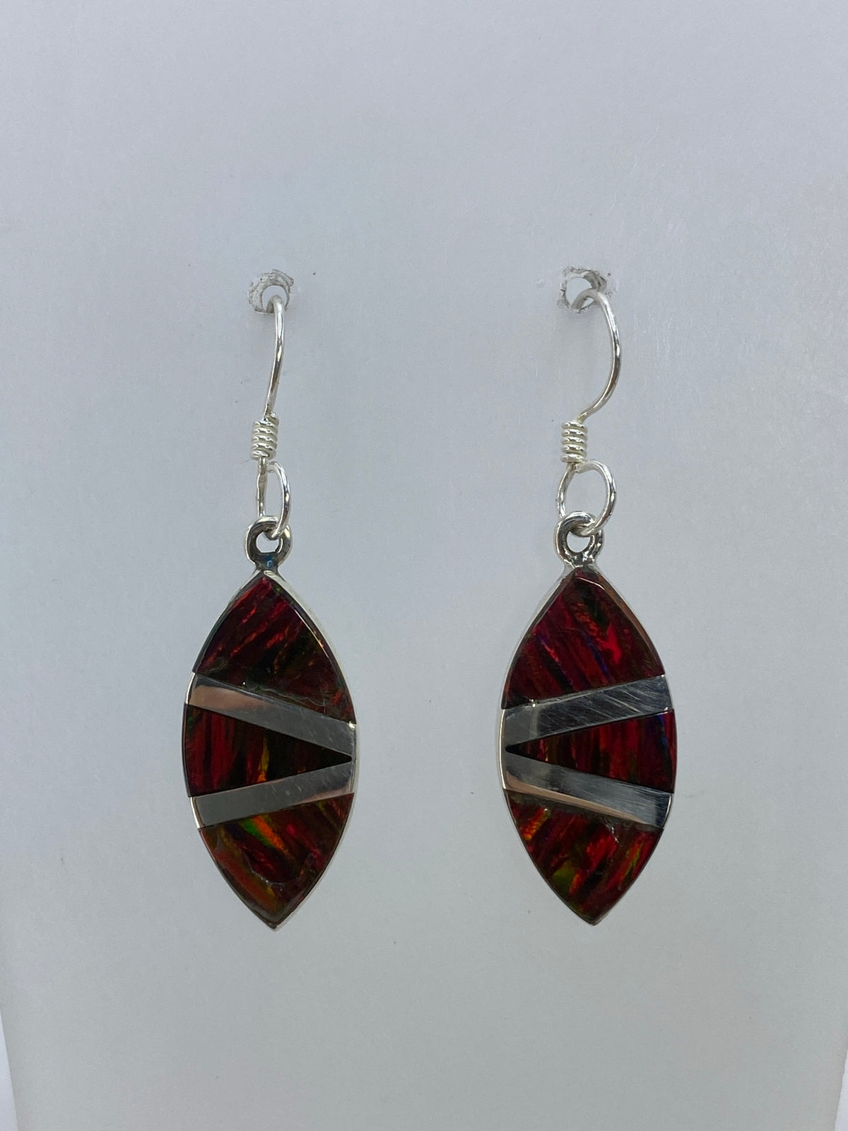 Detalle frontal del ópalo de fuego multicolor en uno de los aretes, mostrando los reflejos rojos, naranjas y verdes