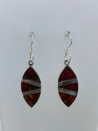 Detalle frontal del ópalo de fuego multicolor en uno de los aretes, mostrando los reflejos rojos, naranjas y verdes