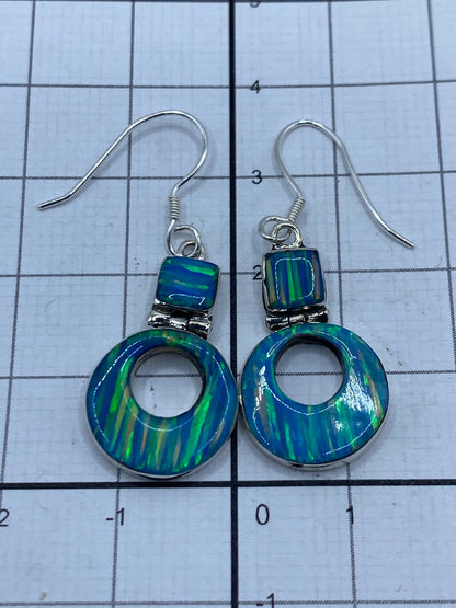 Aretes de opalo sobre balanza de precisión pesando 2.6 gramos, con etiqueta SKU