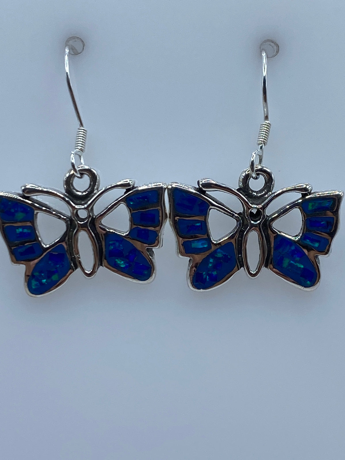 Aretes colgando, mostrando el largo de 2.7 cm y el reflejo azul del opalo