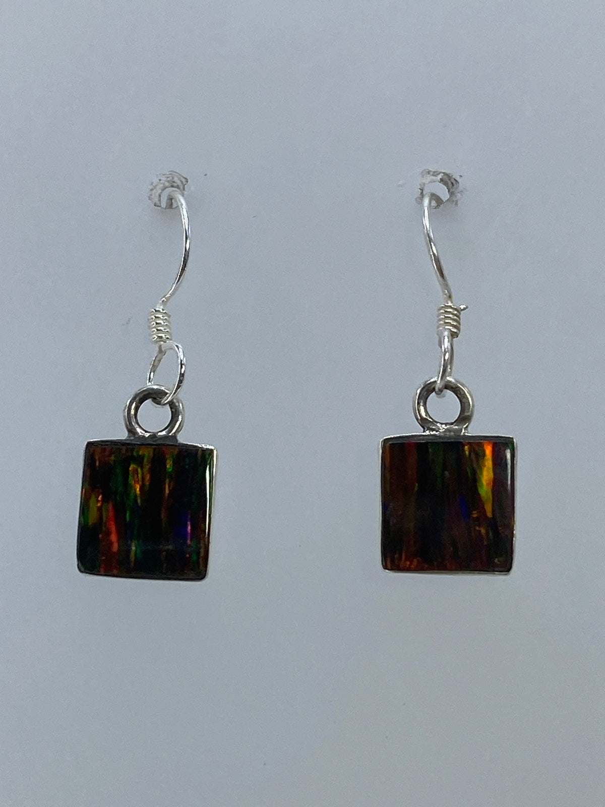 Par de aretes de plata con ópalo de fuego multicolor, junto a escala de medición mostrando 2.3 cm