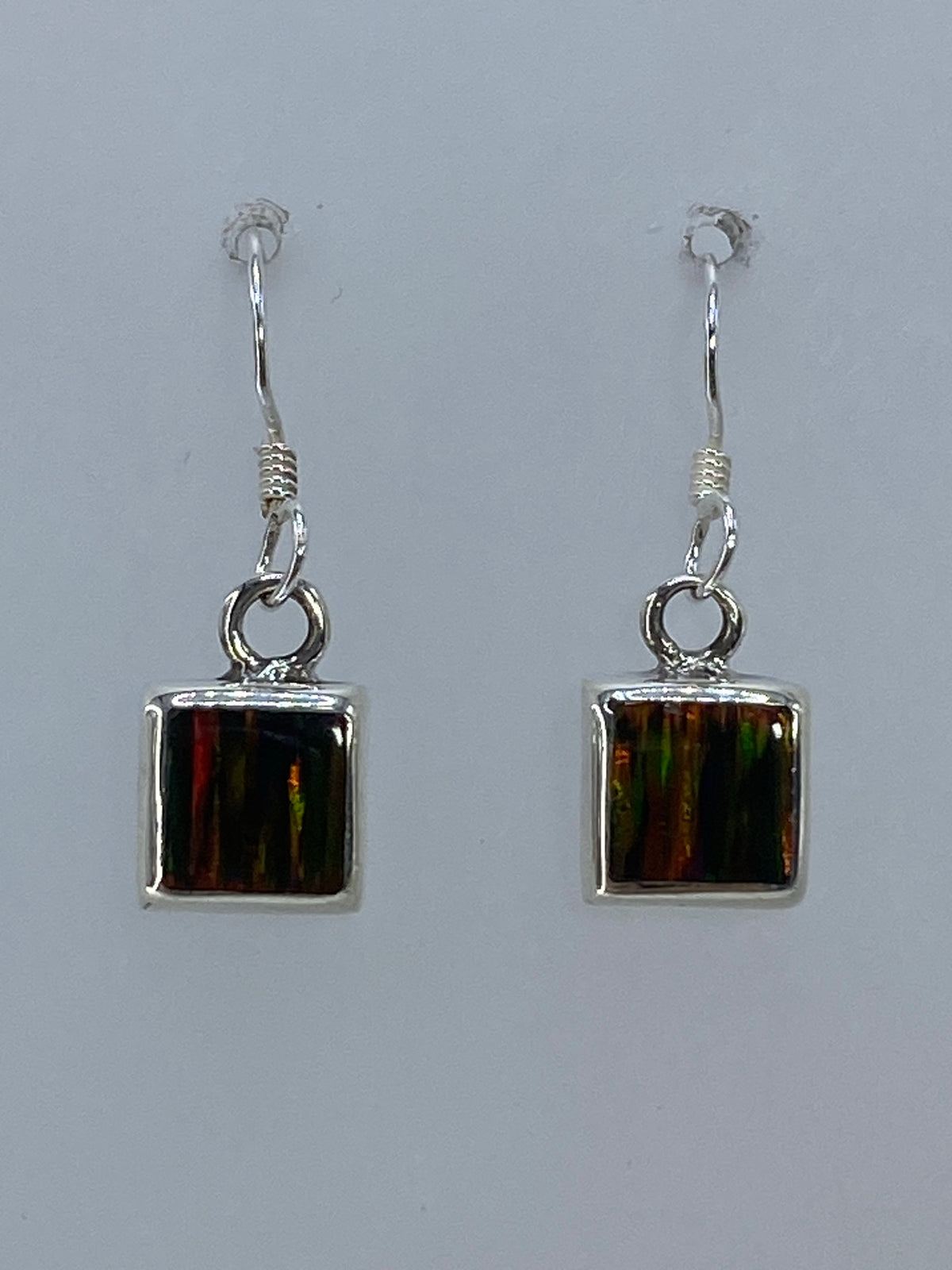 Par de aretes de plata con ópalo de fuego multicolor, mostrando los reflejos rojos y naranjas de la piedra