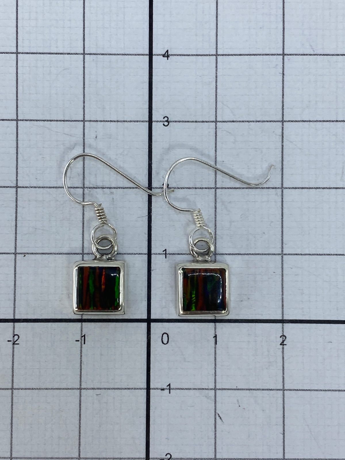 Aretes colgando, mostrando el largo de 2.4 cm y el movimiento de la luz en la piedra