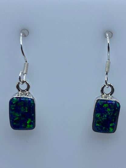Par de aretes de plata 950 con opalo de fuego azul, gancho visible, sobre fondo blanco