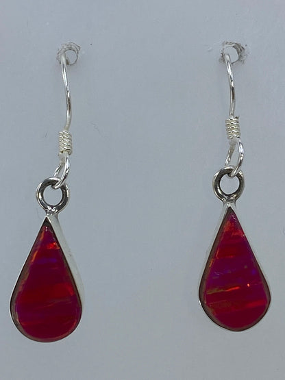 Aretes puestos mostrando el brillo rosa y naranja del ópalo