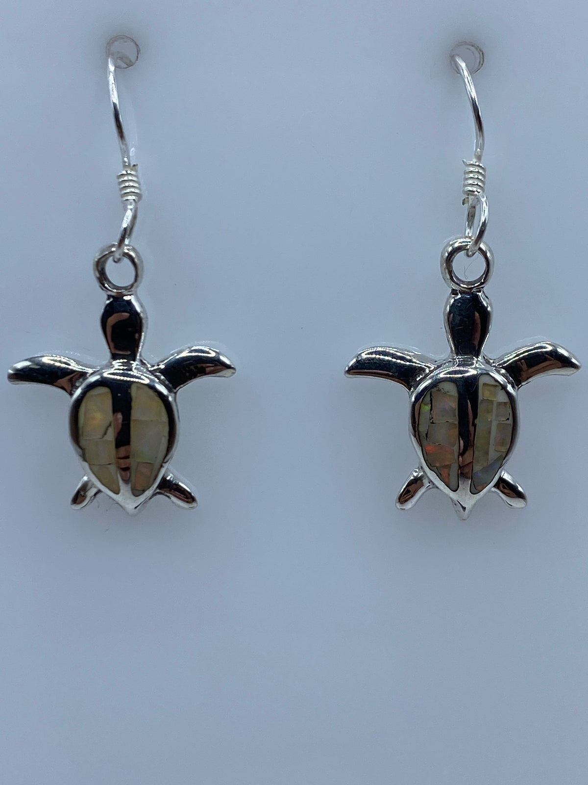 Aretes en la mano mostrando el tamaño y el juego de luz del ópalo