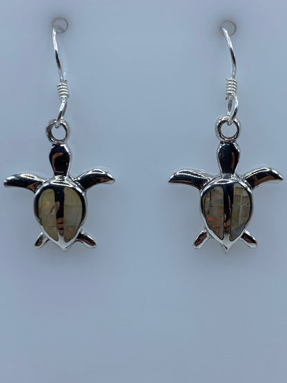 Aretes en la mano mostrando el tamaño y el juego de luz del ópalo
