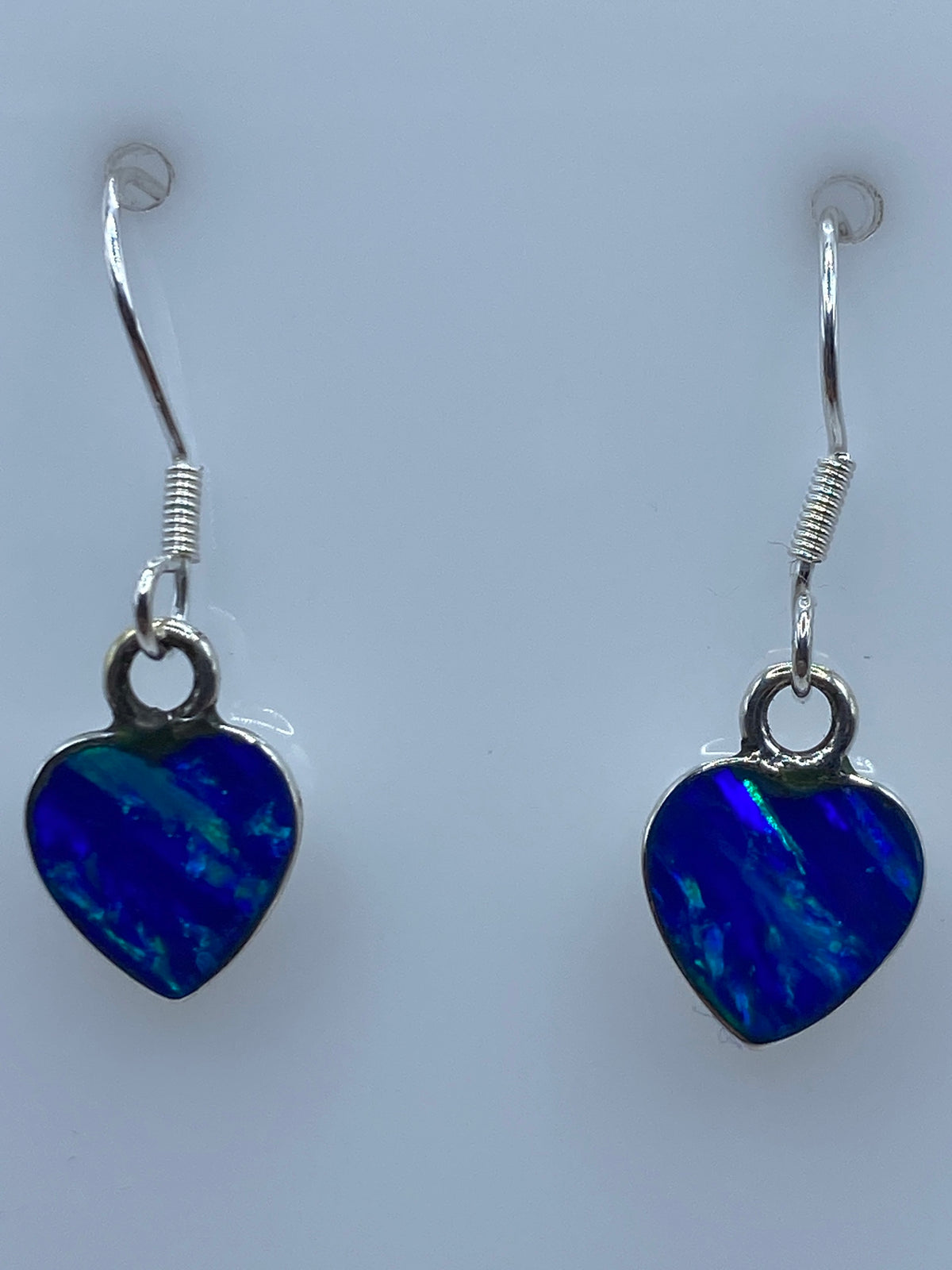 Aretes puestos, mostrando el color azul vibrante del opalo contra la piel