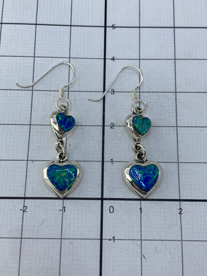 Aretes puestos mostrando el largo de 3.9 cm y el brillo del ópalo de fuego