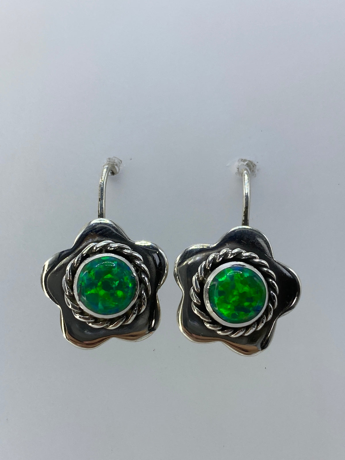 Par de aretes en forma de flor de plata 950 con ópalo de fuego verde limón, vistos de frente