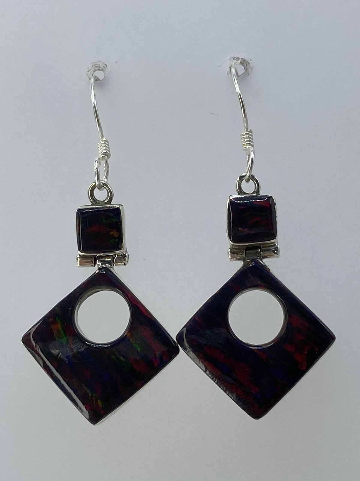 Vista frontal de los aretes: piedras de ópalo con juegos de luz rojo, verde y azul