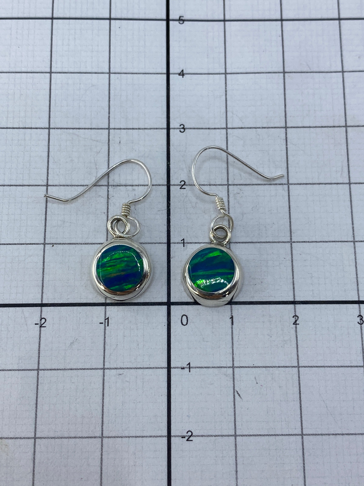 Aretes posicionados mostrando el largo de 2.5 cm y el brillo del ópalo al reflejar luz