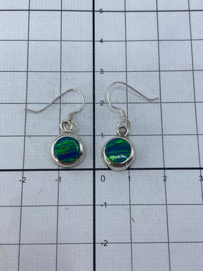 Aretes posicionados mostrando el largo de 2.5 cm y el brillo del ópalo al reflejar luz