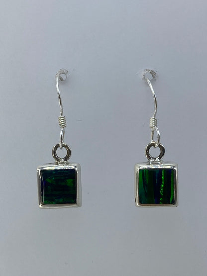 Par de aretes de plata 925 con ópalo de fuego verde limón engastado, colgando sobre fondo blanco
